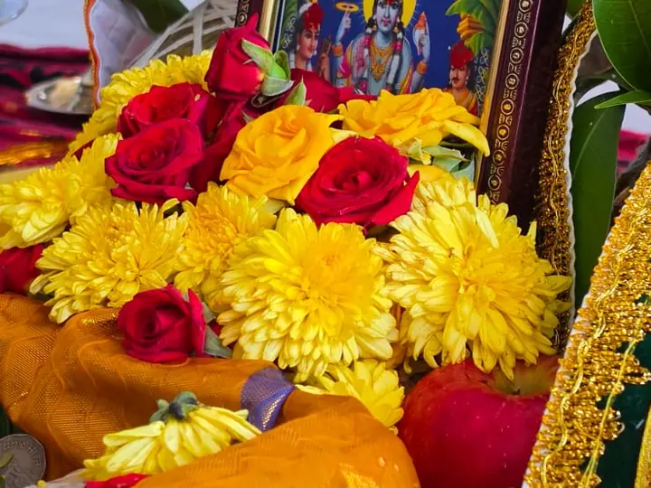 Satyanarayan Swami portrait surrounded by flowers, coconuts and mango leaves