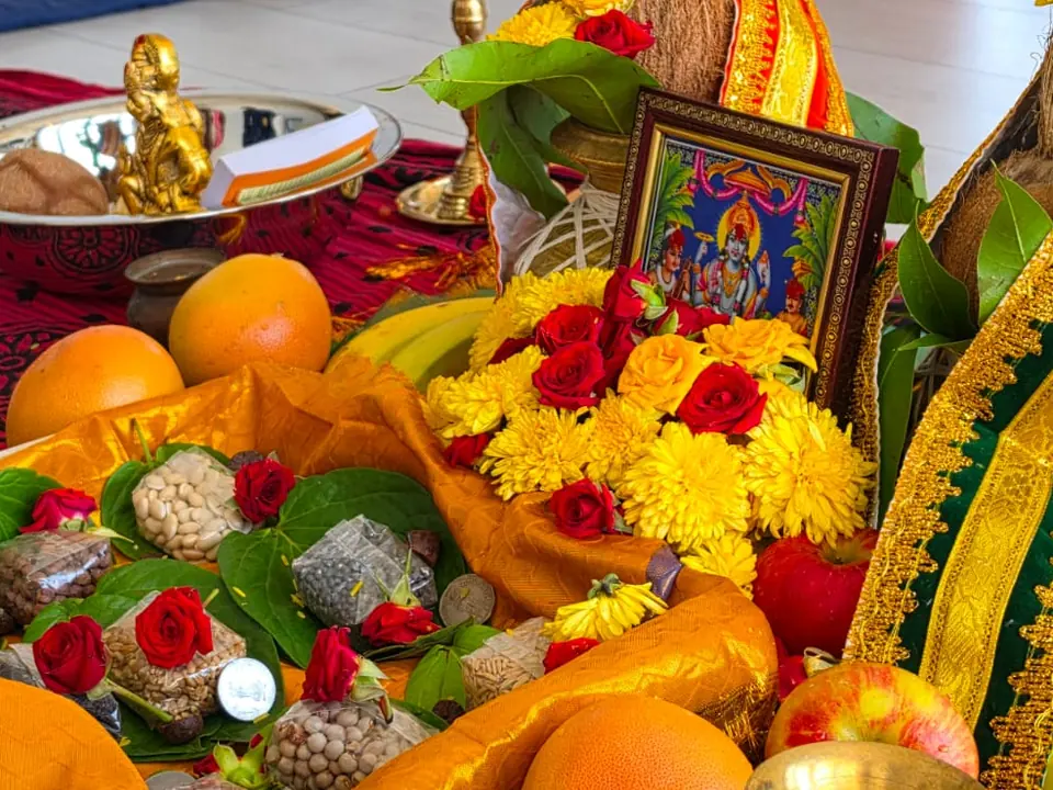 Puja tray with betel leaves, fruits, roses and grains arranged for the ritual